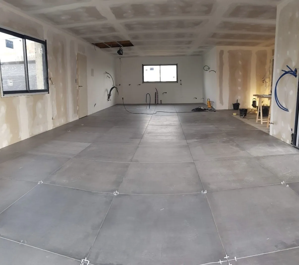Pièce en cours de rénovation avec carrelage grand format posé au sol et croisillons autonivelants encore en place