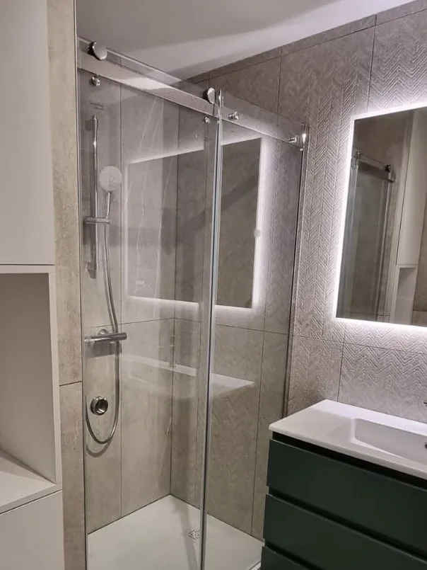 Douche à porte coulissante, carrelage effet béton et chevrons, miroir rétroéclairé et meuble vasque vert
